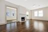 Living area featuring wood flooring, a traditional fireplace with a white mantel, and multi-pane windows