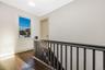 Dark wood-finish flooring, charcoal-painted spindle railing, neutral wall tones, and sash window