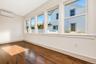 Interior room featuring wood-flooring, a wall-mounted ductless mini-split unit, and a series of oversized windows