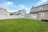 Backyard featuring a manicured lawn, full-perimeter vinyl privacy fencing, exterior siding, multi-pane windows, and a structured garden bed. Grass is 
