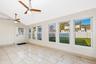 All seasons room surrounded by oversized windows, ceramic tile flooring, and a ceiling fan