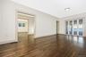 Living room featuring wood flooring, white walls, wide cased openings, and multi-pane glass doors leading to the all seasons room
