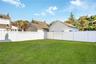 Expansive backyard featuring a level lawn and a full-height white vinyl privacy fence with lattice detailing. Grass is virtually enhanced
