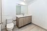 Floating vanity with wood-finish cabinetry, solid-surface countertop, rectangular integrated sink, wall-mounted bronze-tone faucet, and floor-to-ceili