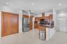Kitchen featuring wood cabinetry, stone countertops, stainless steel appliances, tile flooring, and recessed ceiling lighting