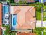 Aerial perspective of a residential property featuring a tiled roof, an in-ground swimming pool with an integrated spa, a concrete pool deck, and a fe