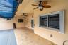 Covered patio featuring stone-tiled flooring, dual ceiling fans, a retractable blue canopy, and sliding glass entry doors