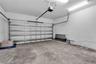 Attached garage featuring concrete flooring, an automated overhead door system, and ceiling-mounted fluorescent lighting