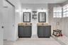 Dual-vanity bathroom featuring stone-surfaced countertops, charcoal-finish cabinetry, framed mirrors, and a glass-enclosed shower with tiled wall surr