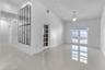 Vaulted ceiling, neutral large-format tile flooring, decorative grid-pattern wall mirror, glass-paned interior door, and double glass-paned exterior d