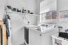 Laundry room featuring a single-hung window, white metal shelving, and a wall-mounted multi-compartment dispenser