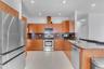 Kitchen featuring wood cabinetry, stone countertops, stainless steel appliances, a tile backsplash, and recessed lighting