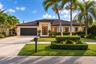 Single-story exterior featuring a tile roof, stone masonry facade, multi-panel glass entry door, and paved driveway