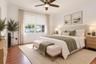 Neutral-toned interior featuring wood-finish flooring, a multi-blade ceiling fan with integrated lighting, dual-pane windows, and minimalist wall mold