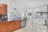 Kitchen featuring wood-finish cabinetry, stone-surface countertops, stainless steel dishwasher, recessed lighting, and tile flooring