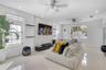 Living area featuring a floor-to-ceiling textured stone accent wall, large-format tile flooring, recessed ceiling lighting, and dual ceiling fans