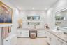 Stone-veneer feature wall with stacked horizontal windows, white cabinetry with integrated vanity, rectangular vessel sink, and illuminated vanity mir