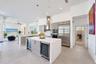 Kitchen featuring light-finish cabinetry, a large central island with a solid surface countertop, stainless steel appliances, dual beverage coolers, a