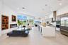 Open-concept living space featuring a central kitchen island with waterfall-edge stone countertop, built-in recessed shelving, integrated linear firep