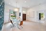 High-ceilinged room featuring large-format tile flooring, a prominent patterned accent wall, recessed lighting, and a chandelier with textured detail