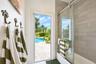 Bathroom featuring a sliding glass shower door, rectangular tile wall surround, and exterior door with access to a patio and pool