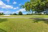 Expansive green space featuring golf course fairways, sand bunkers, paved cart paths, and mature landscaping