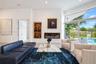 Modern living space featuring a built-in electric fireplace, recessed wood-trimmed shelving, large-format tile flooring, and floor-to-ceiling glass sl