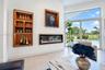 Built-in illuminated wood shelving, recessed linear electric fireplace, large-format tile flooring, and floor-to-ceiling sliding glass doors with outd