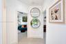 Interior hallway featuring large-format tile flooring, neutral wall finishes, and dual circular wall-mounted mirrors with wood-toned frames