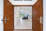 Double wood-finish entry doors featuring horizontal paneling and brushed metal hardware, complemented by a transom window and large-format tile floori