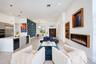 Open-concept interior featuring large-format tile flooring, a wall-mounted linear electric fireplace with wood trim, built-in recessed shelving, a cen