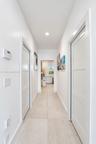 Hallway featuring large-format tile flooring, three-panel interior doors, and recessed lighting