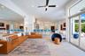 Open-concept interior featuring large-format tile flooring, expansive glass sliding doors, dual built-in fireplaces, a ceiling fan, and recessed light