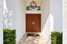 Entryway featuring double wood-finish doors with horizontal paneling, a circular metal orb pendant light fixture, a rectangular transom window, and st