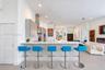 Kitchen featuring quartz countertops, wood-finish cabinetry, stainless steel range hood, built-in wall oven, and tile backsplash