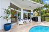 Covered patio featuring stone tile flooring, a swimming pool, multiple sliding glass door sets, and a ceiling-mounted fan