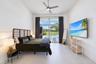 High-ceilinged room featuring large-format tile flooring, a brushed metal ceiling fan, and floor-to-ceiling sliding glass doors opening to an exterior