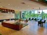 Open-concept interior featuring floor-to-ceiling glass walls, large-format stone-finish flooring, a linear built-in fireplace, and expansive built-in 