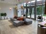 Open-concept space featuring stone tile flooring, floor-to-ceiling glass windows, an integrated pergola structure, and multi-pendant lighting fixtures