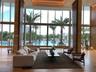 Double-height floor-to-ceiling windows, stone flooring, decorative slatted wood-finish columns, recessed architectural ceiling lighting, and exterior 