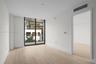 Floor-to-ceiling windows, wood-finish flooring, and an attached balcony with dark metal railings