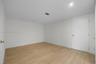 Neutral-toned room featuring light wood-finish flooring, white walls, and a white interior door with metallic hardware
