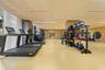 Fitness area featuring textured wood-panel ceiling, mirrored structural pillars, circular accent mirrors, recessed linear lighting, and resilient athl