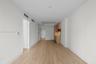 Light-toned wood-finish flooring, recessed ceiling lighting, and minimalist cabinetry with light-colored finish and metallic fixtures