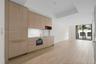Modern kitchen featuring light wood-finish cabinetry with integrated appliances, brass-finish hardware, a tiled backsplash, and wood-finish flooring