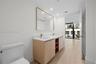 Master bathroom Dual-sink vanity with light wood cabinetry, white stone countertop, rectangular undermount sinks, and gold-tone fixtures, complemented