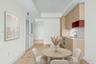 Kitchen featuring light wood-finish cabinetry, an integrated cooktop, a built-in oven, a brass-tone faucet, and a stone-finish countertop - staged