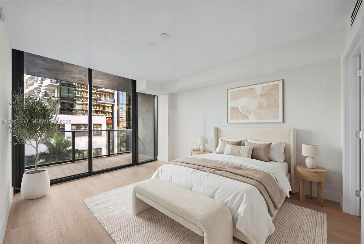 Floor-to-ceiling glass sliding doors, wood-finish flooring, and a private balcony with black metal railings - staged
