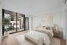 Floor-to-ceiling glass sliding doors, wood-finish flooring, and a private balcony with black metal railings - staged