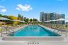 Rooftop lap pool featuring a tiled basin, aggregate pool deck, metal handrails, and a dedicated drainage perimeter
